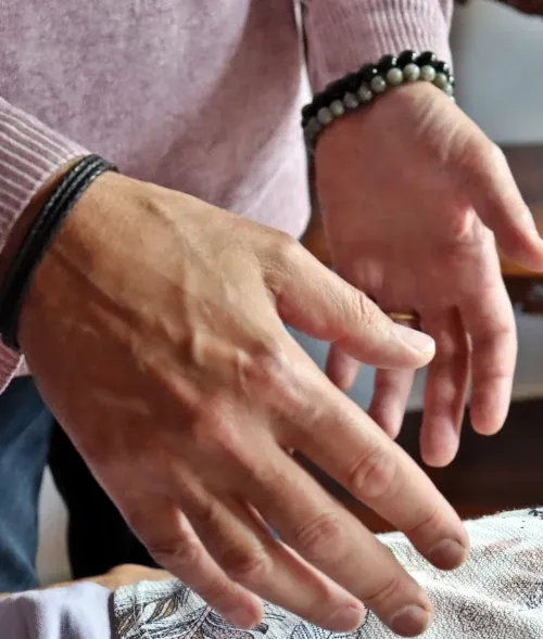 Gros plan sur les mains de Luc Turell en imposition pendant une séance.